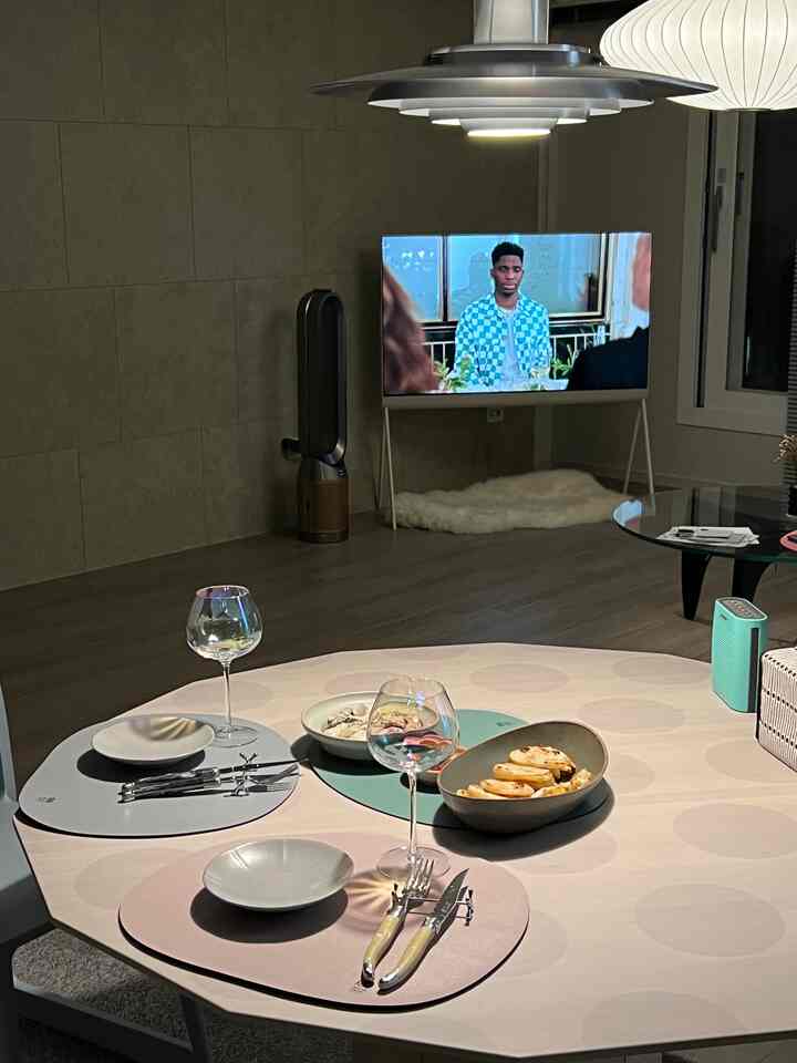 A natural-toned living room featuring a round dining table set with tableware and wine glasses in a simple, cozy atmosphere