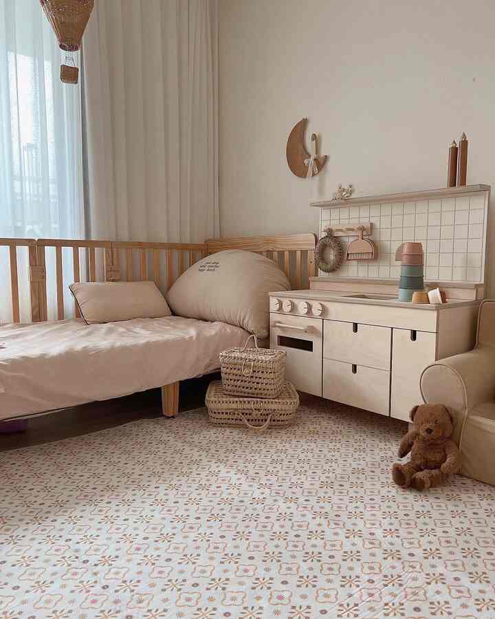 柔らかなベージュとナチュラルウッドの調和が感じられる子供部屋、ベビーベッドとキッチン玩具が配置された温かみのあるインテリア