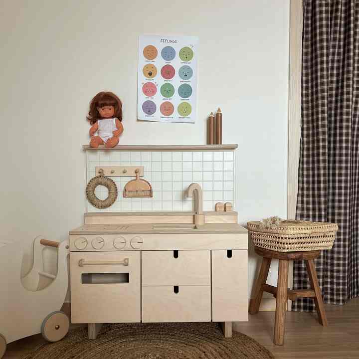 Beige-toned kids' room featuring natural wood play kitchen, rattan rug, and brown checked curtain for a cozy atmosphere