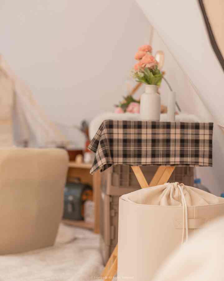 温かみのあるナチュラルカラーのキャンピングキッチン、チェック柄のテーブルクロスとレザー製のハンパーが配置された雰囲気のある空間