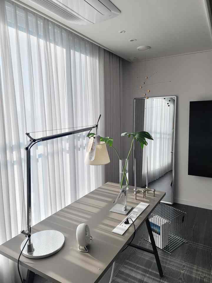 Modern and organized home office space in white and gray tones featuring bright curtains and a full-length mirror