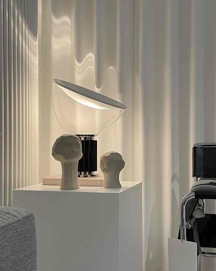 White-toned living room featuring a Mid-Century Modern table lamp and abstract objet sculptures centrally placed, showcasing a clean interior design