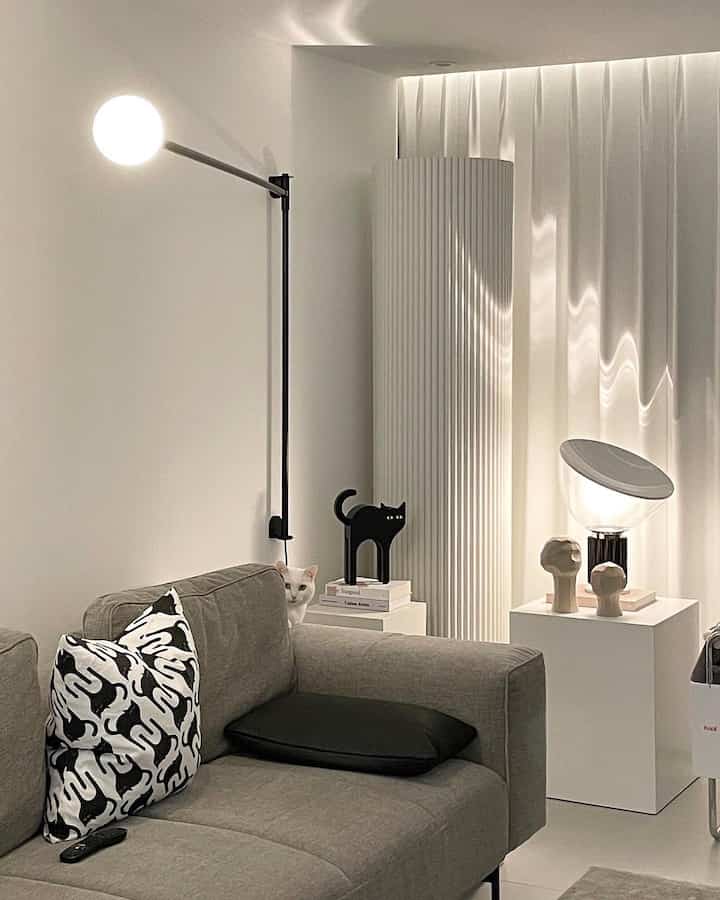 White and gray toned living room featuring a gray sofa, cat objet, and soft lighting in a modern setting