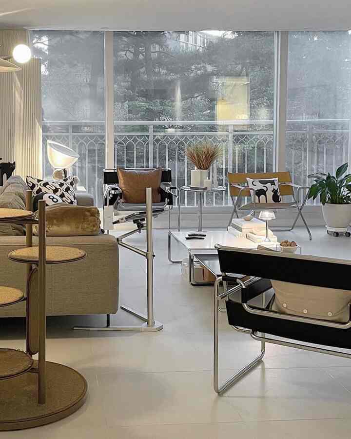 White and brown toned living room featuring mid-century modern armchairs and a cat tower, creating a cozy and stylish atmosphere
