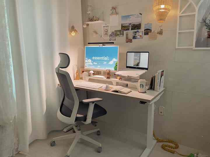 White-toned home office featuring a motion desk and ergonomic office chair in a clean and comfortable workspace