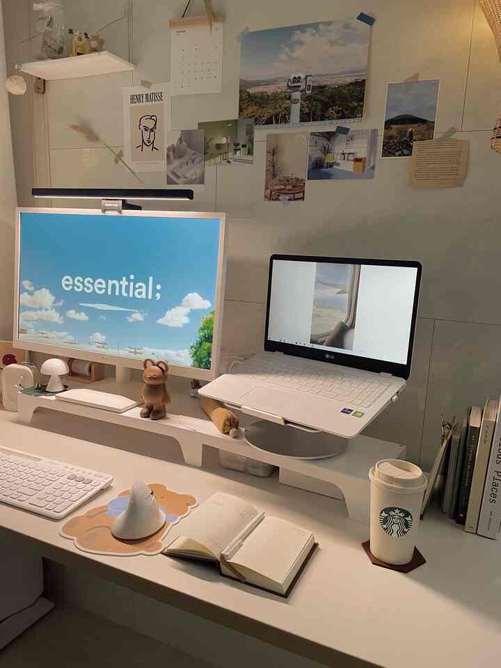 Bright white-toned home office with a white desk, 27-inch monitor, and laptop arranged in a clean, spacious workspace