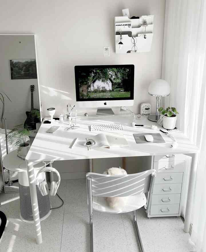 White and natural tone single-person home office featuring a neat desk and lamp with a bright and spacious atmosphere