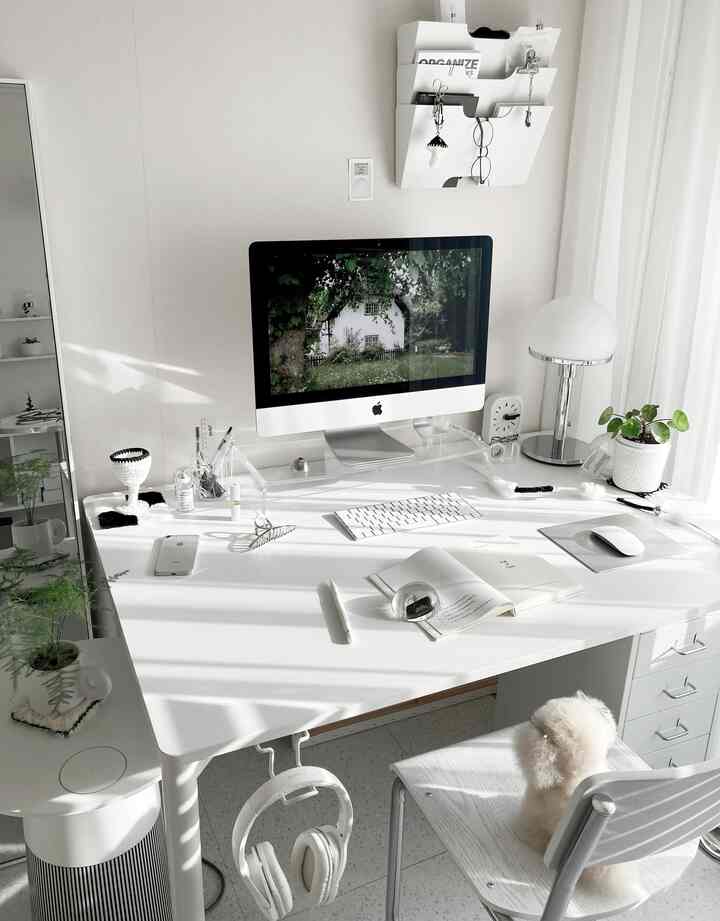 明るいホワイトトーンのホームオフィス、広いデスクにAppleのiMacとシルバートーンのテーブルランプが配置されたシンプルモダンなインテリア