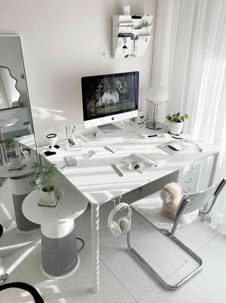 White-toned workspace featuring a desk with iMac and digital devices in a simple, modern interior