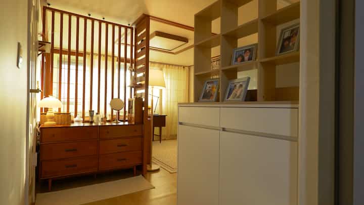 Beige and wood-tone powder room and entrance space featuring partition, dresser, and shoe cabinet with warm atmosphere