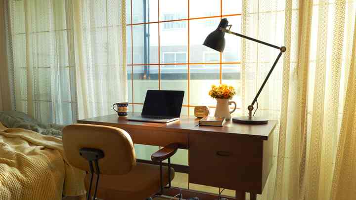 暖かいイエローとブラウンのトーンが調和したベランダのホームオフィス、木製デスクとヴィンテージチェアがクラシックで居心地の良い空間を演出