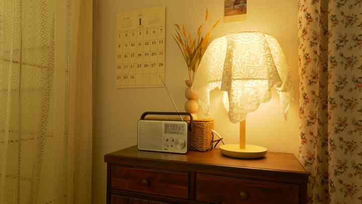 Cozy space near veranda with warm ivory and brown tones featuring vintage radio on wooden nightstand and lace curtains