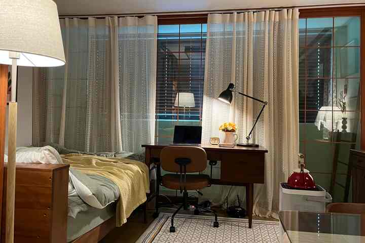 Natural modern bedroom and home office featuring ivory curtains and wood tone furniture, creating a warm atmosphere