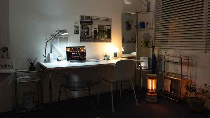 白とグレーの色調のホームオフィス、机とオフィスチェアが配置され、電気ヒーターが温かみのある雰囲気を演出する印象的な空間