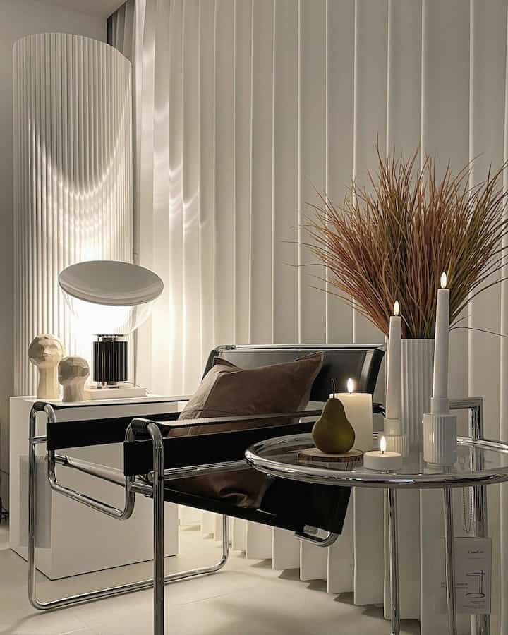 A white, black, and brown toned living room featuring a mid-century modern armchair and LED candles creating a cozy atmosphere