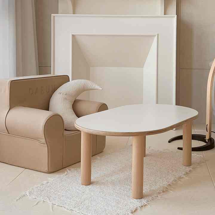 ベージュとアイボリーの色調の子供部屋兼リビングスペース、幼児用ソファとミニテーブルが配置された雰囲気のあるインテリア