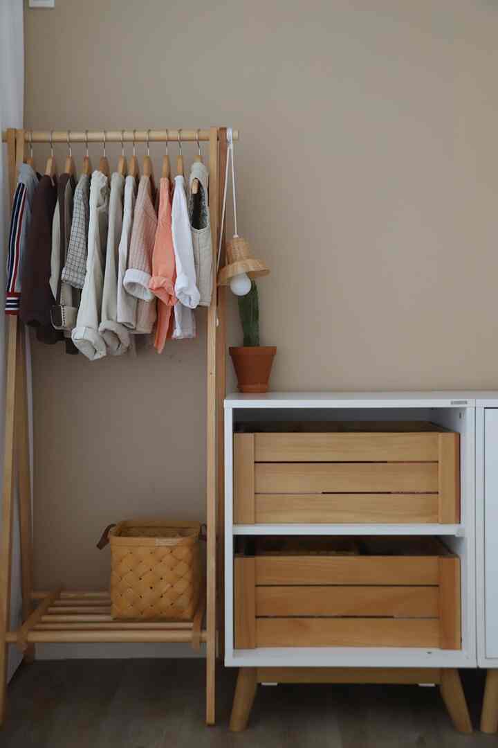 Natural beige-toned kids' room featuring a wooden hanger stand and wooden drawer storage with organized clothing