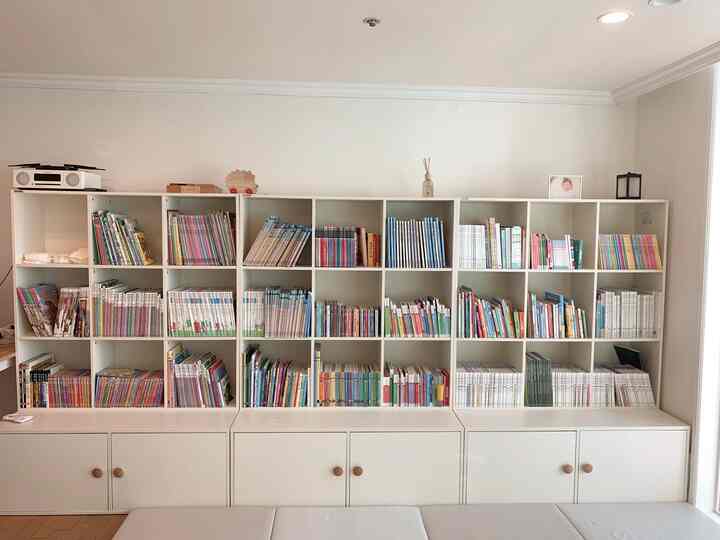 Bright white kids' room featuring a large bookshelf filled with children's books, creating a clean and simple atmosphere