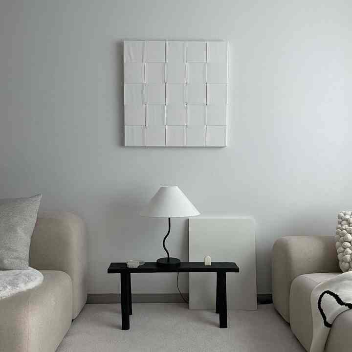 Beige and black toned living room featuring sofas on both sides, a central black bench with lamp, in a modern and minimalist setting