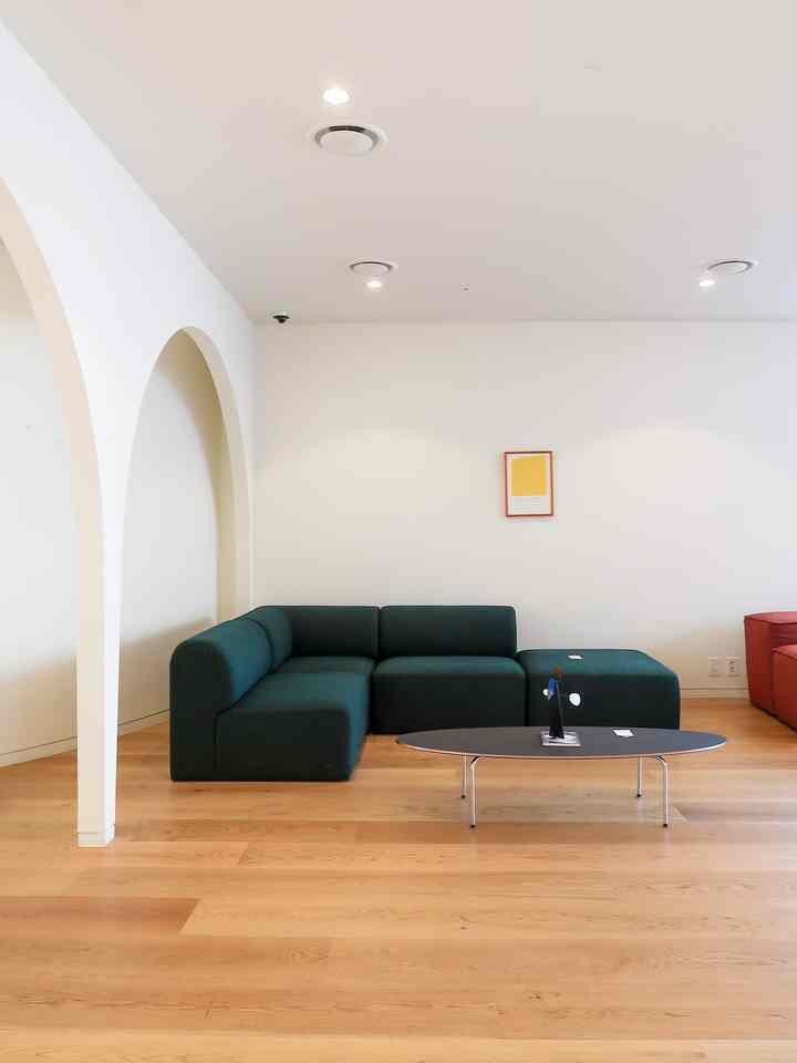 Simple living room with dark green sectional sofa and oval coffee table on natural wood flooring