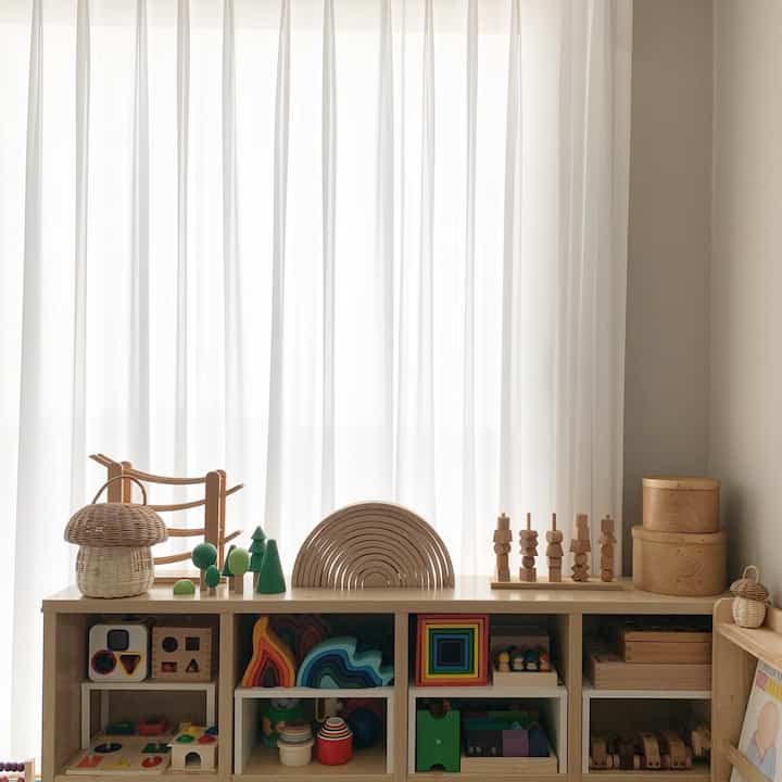 ナチュラルな木目調とアイボリーの色調が特徴の子供部屋、教育玩具を整然と収納した印象的な本棚が配置された空間