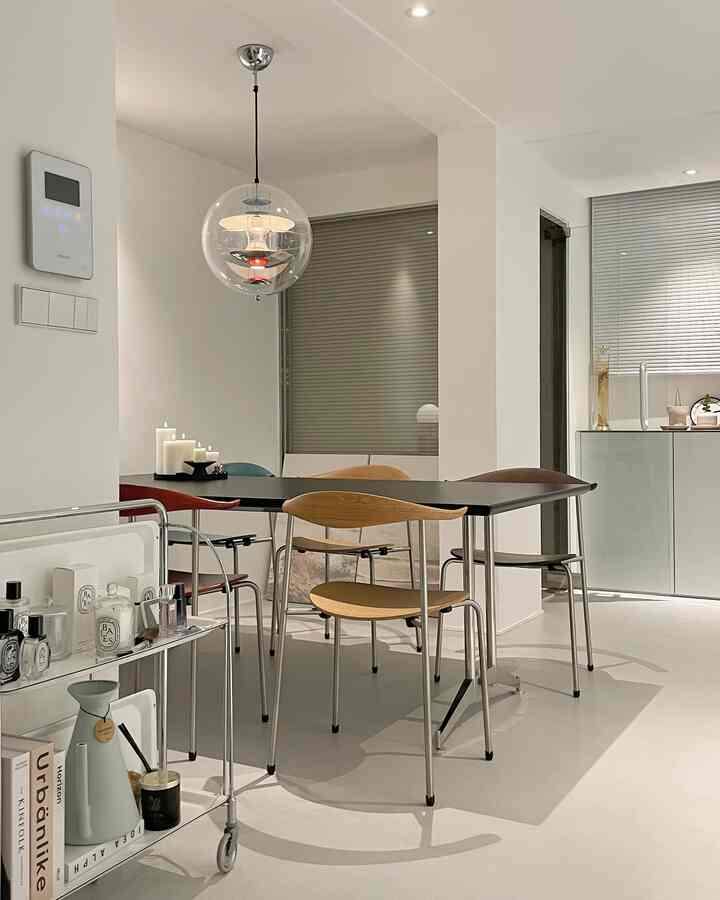 ホワイトと木目調が調和するミッドセンチュリーモダンのキッチンダイニングルーム、ブラインドとキャンドル、キッチンワゴンが配置された雰囲気のあるインテリア