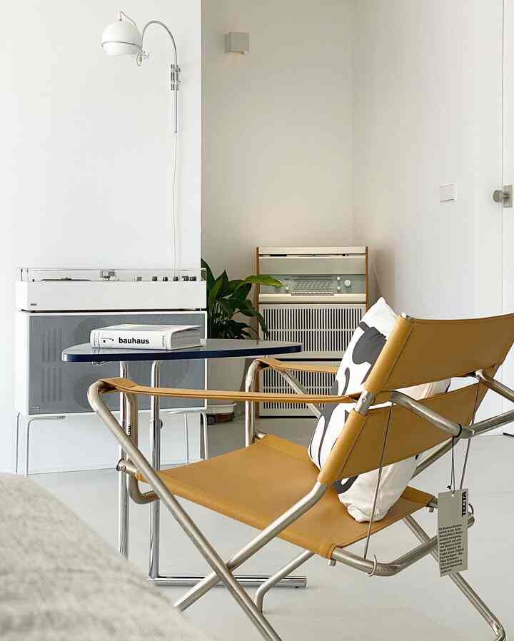 Simple modern living room with white background and a yellow leather Tecta Bauhaus chair