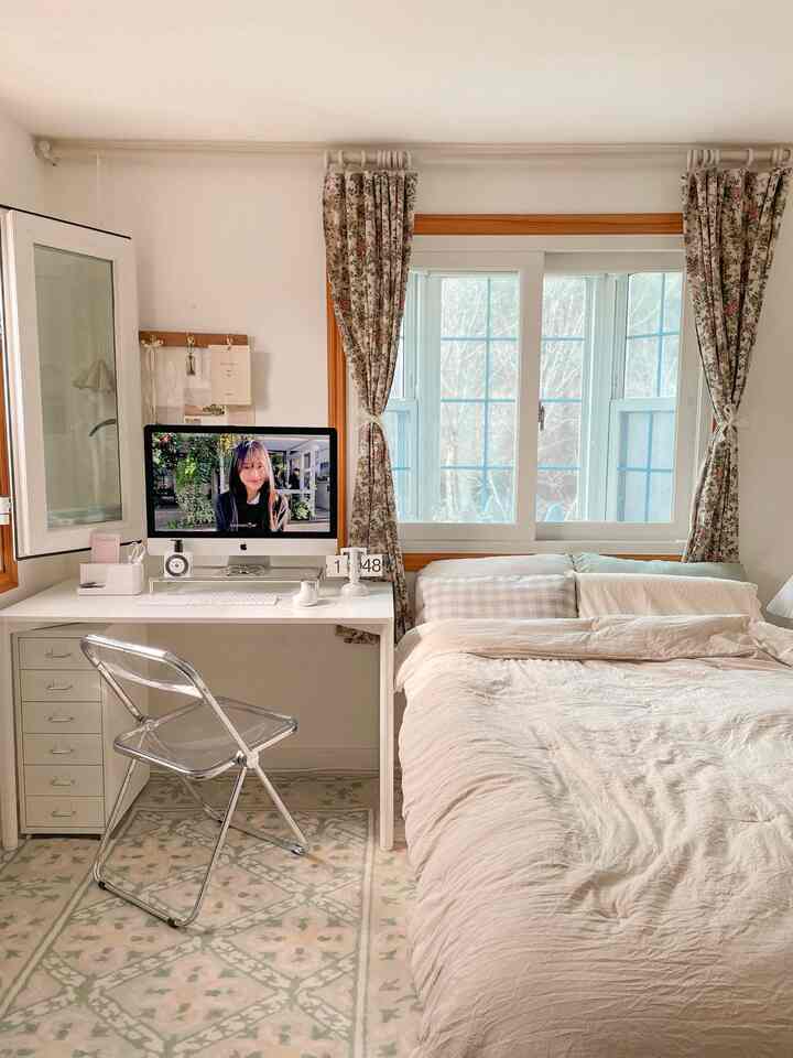 Cozy compact home office bedroom in white and beige tones featuring a desk and bed with natural lighting