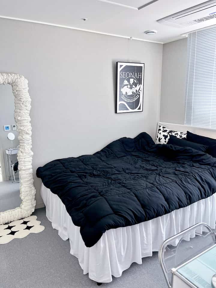 Monotone bedroom featuring black bedding and white bed skirt, clean and modern space with minimal decor