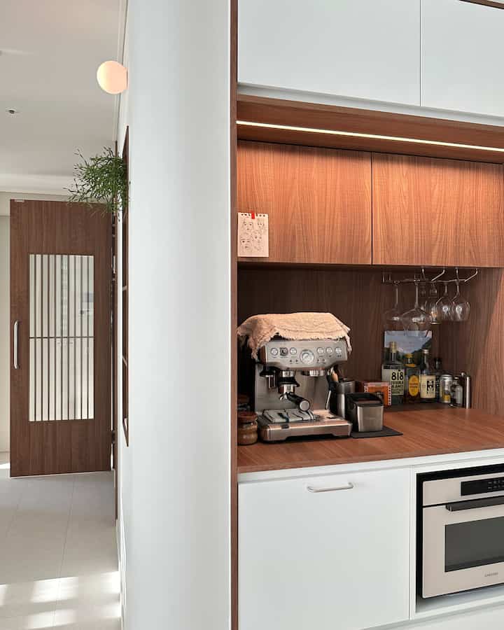 Clean white and wood tone kitchen space featuring Breville coffee machine and home bar creating a cozy atmosphere