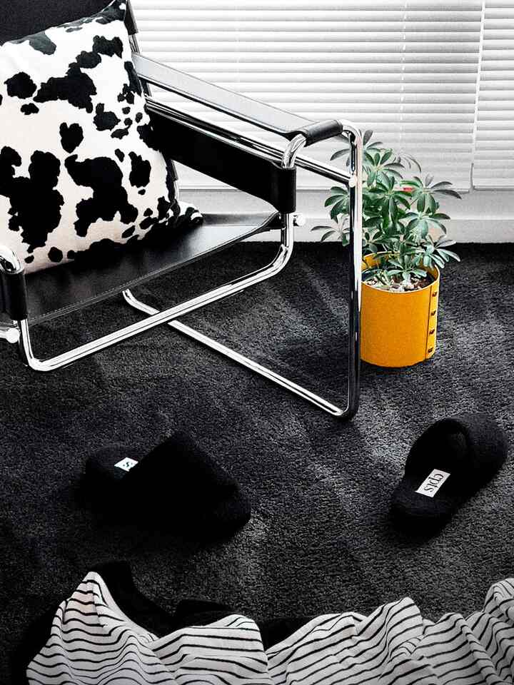 Living room with black metal armchair, black rug, and a yellow plant pot, showcasing a modern monochrome style