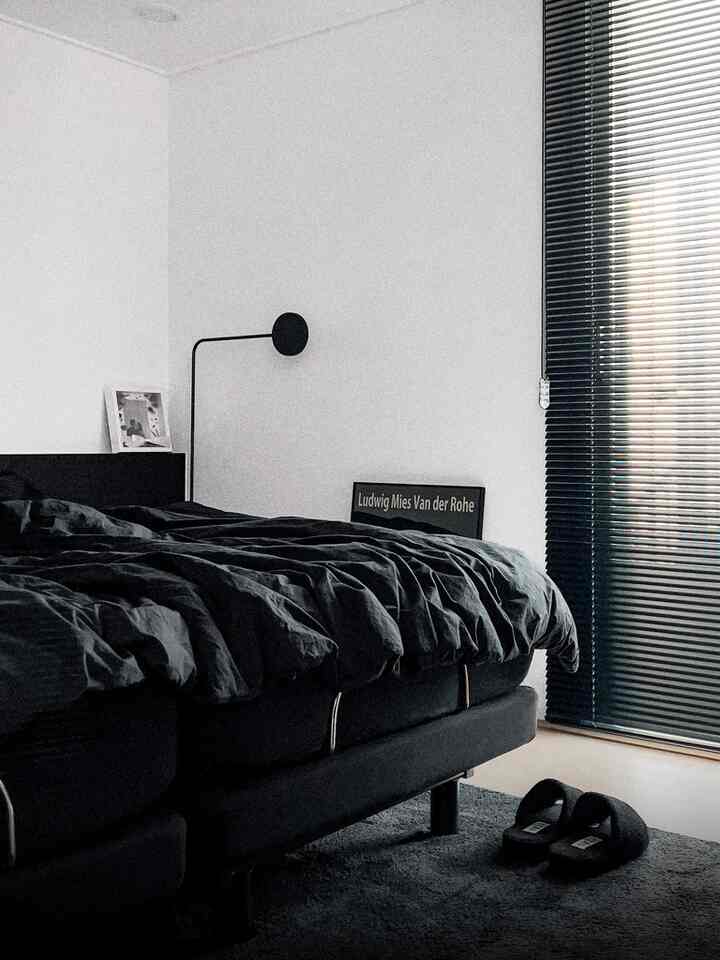 黒と白の色調の寝室、分かれた黒いベッドとブラインドが配置されたミッドセンチュリーモダンな雰囲気のあるインテリア