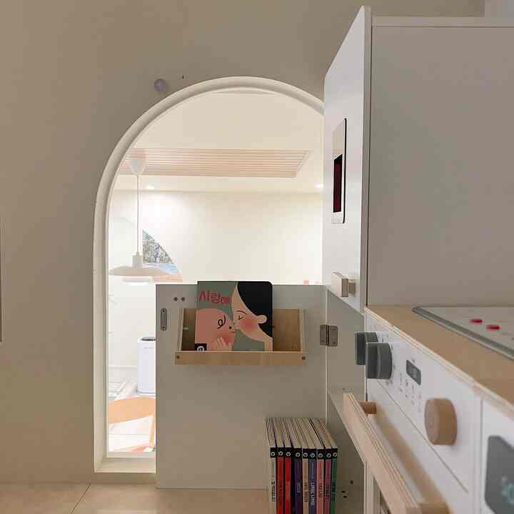 ナチュラルカラーのキッチンスペース、赤ちゃん用家具とクラシックなペンダントライトが配置された雰囲気のあるインテリア