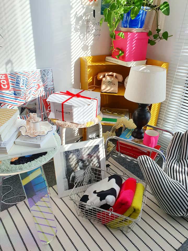 Colorful dining room featuring a bright yellow corner shelf with red accents, various decorative objects, and patterned sofa creating a lively atmosphere