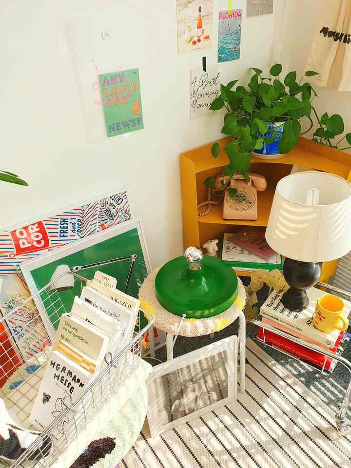 Bright white wall with mustard yellow corner shelf, green plant, and vintage interior accessories in a cozy space