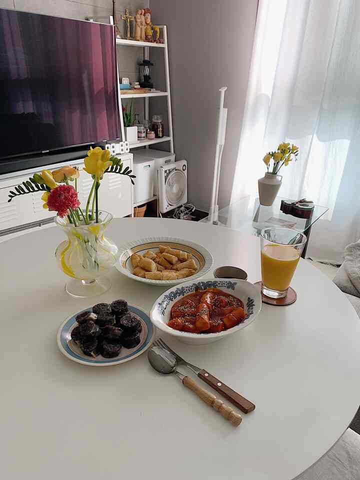 White-toned living room with round table featuring vase and food, creating a cozy atmosphere