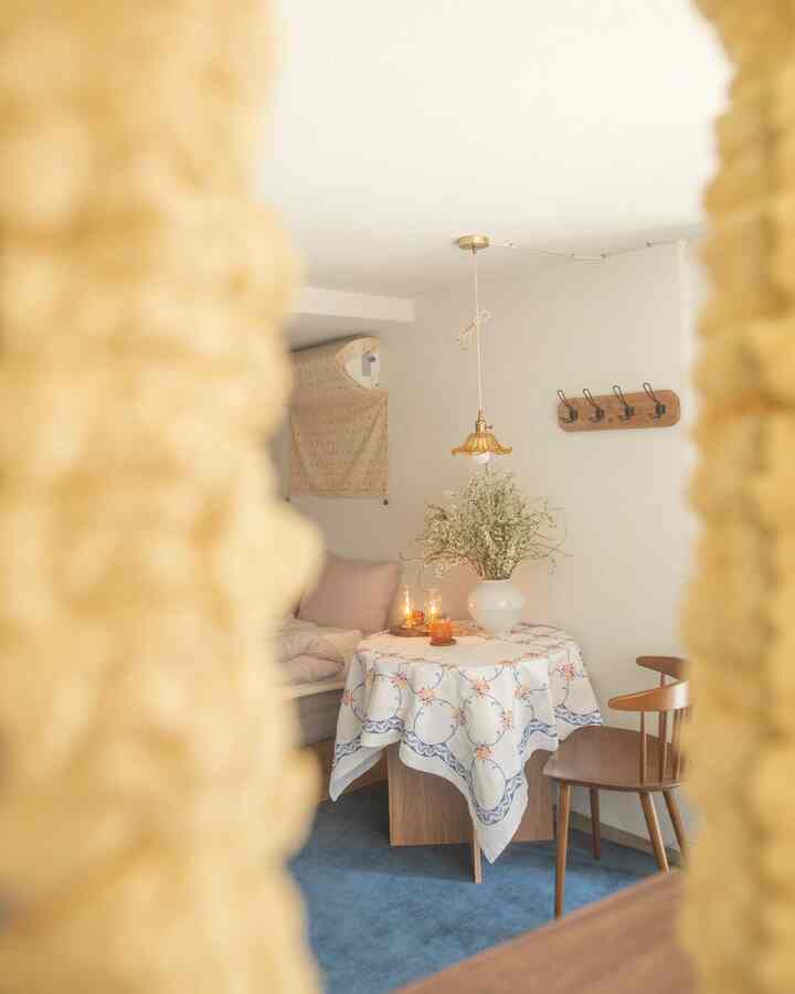 Vintage dining room with warm wood tones and a blue carpet, featuring a round table with floral tablecloth and antique pendant light centerpiece