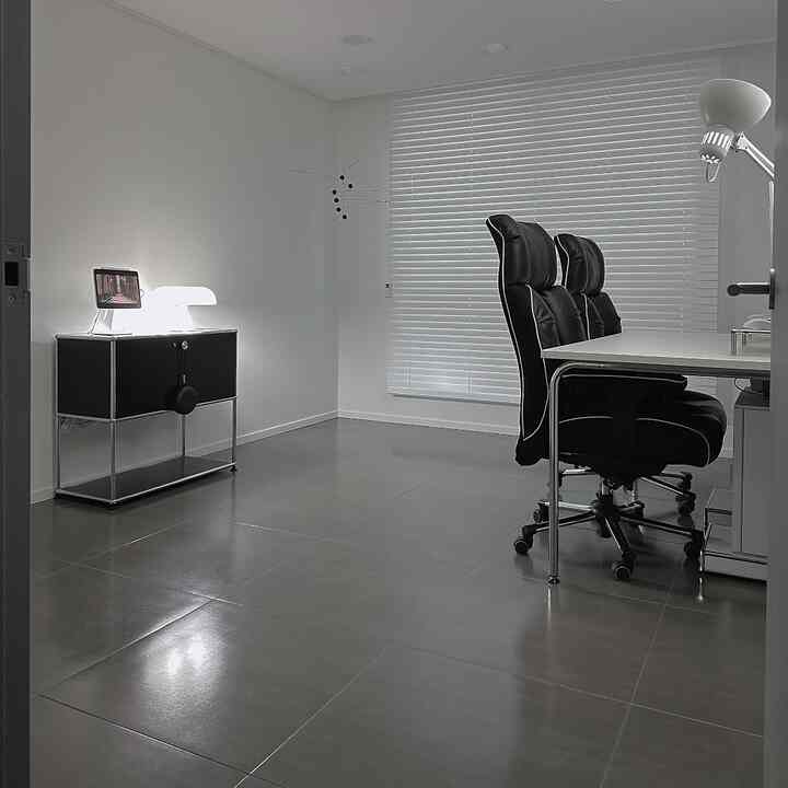 Minimalistic home office with white and black tones, featuring office chairs, desk, and blinds for a modern clean look