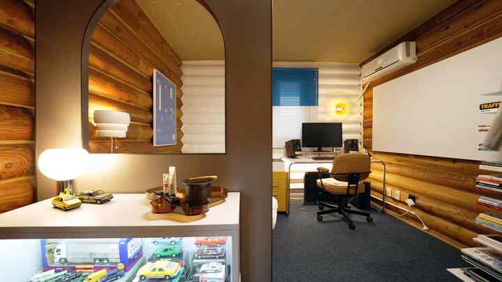 ナチュラルな色調の丸太壁とブルーのカーペットが調和する書斎、モダンな家具とパソコンデスクが配置された落ち着いた空間