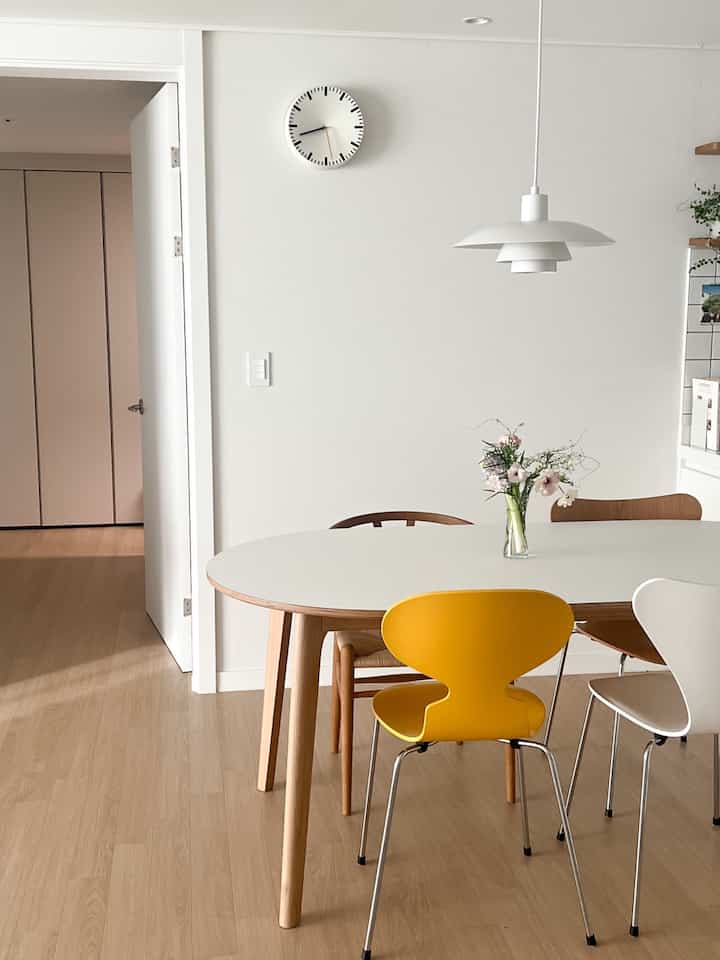 ホワイトと木目調が調和したダイニング、シンプルなダイニングテーブルとカラフルな椅子が配置された清潔感のある空間。