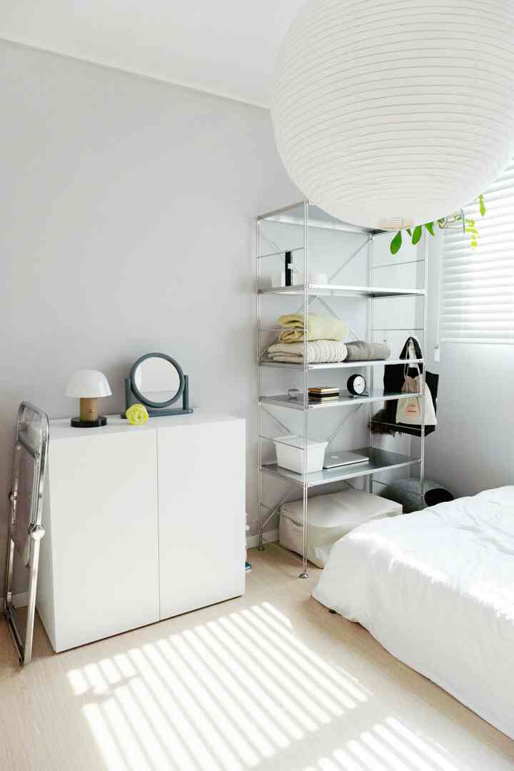 Minimal modern bedroom in white and natural tones, featuring streamlined storage furniture and lighting for a clean atmosphere