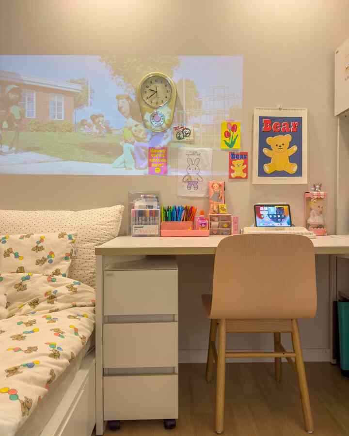 ホワイトとナチュラルカラーの子供部屋、ベッドとデスク、壁時計、カラフルな子供用インテリアが配置された雰囲気のある空間