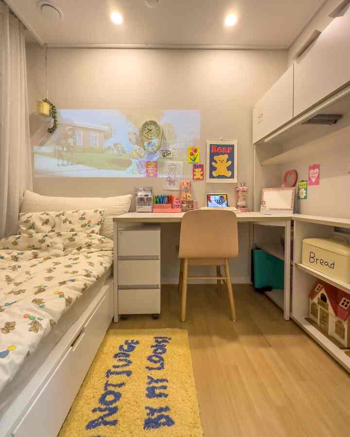 白と黄のトーンの子供部屋、デスクやベッド、壁に子供の絵が飾られた雰囲気あるインテリア