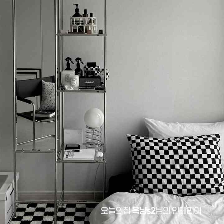 ブラックとホワイトのトーンの寝室、チェッカーボードクッションとメタルシェルフが配置されたモダンなインテリア