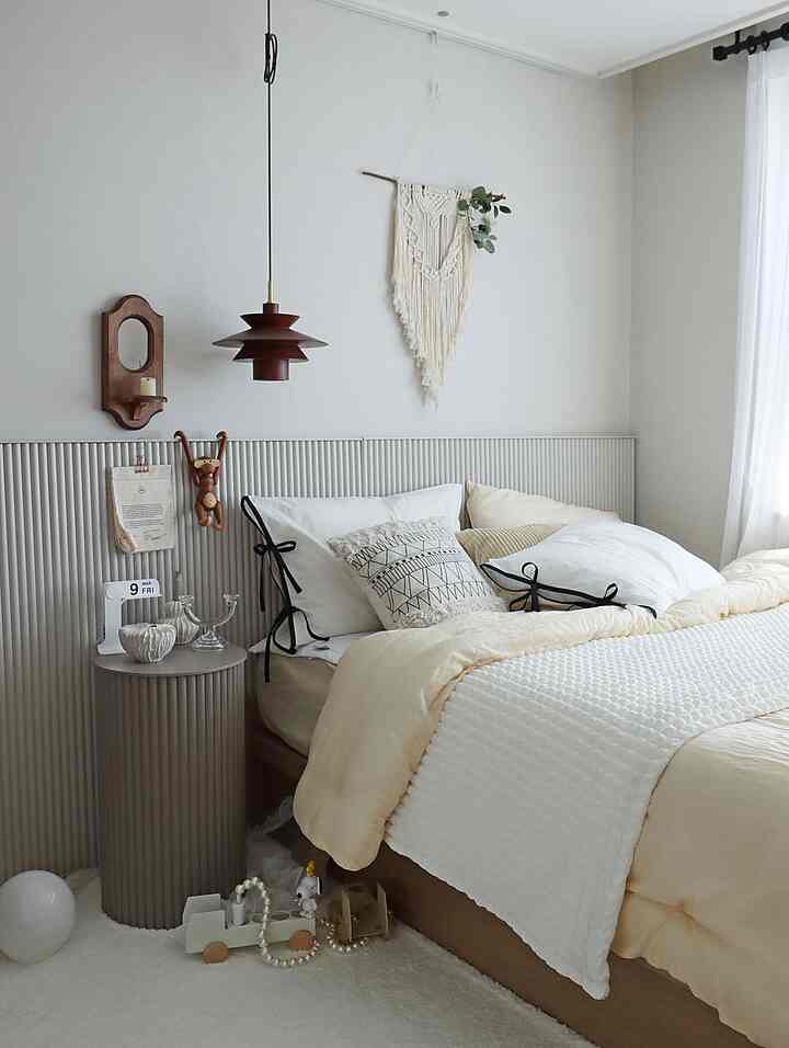 Beige and white toned bedroom featuring a natural modern bed, nightstand, and macrame wall art with a cozy atmosphere
