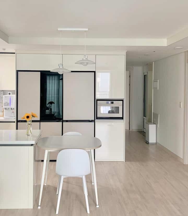 White-toned kitchen in a 20-pyeong apartment featuring a compact dining table and chairs with a simple modern interior design