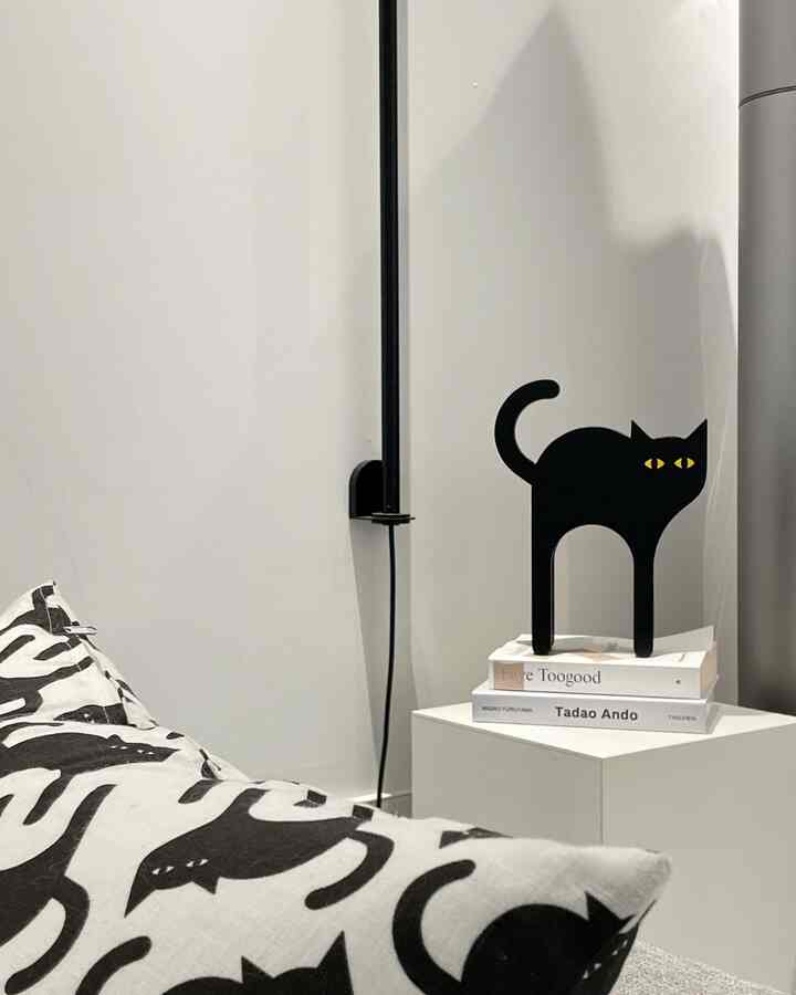 白と黒のトーンのリビング、猫のプリントクッションと猫型オブジェが配置されたモダンな空間