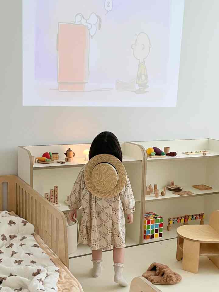 Bright white and wood-toned kids' room featuring a child's bed and toy storage with a cozy atmosphere