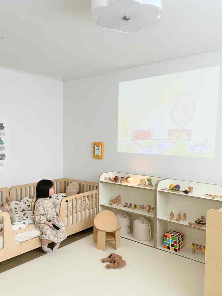 Cozy kids' room for a 5-year-old girl featuring warm ivory tones and birch wood furniture with neatly organized toy storage