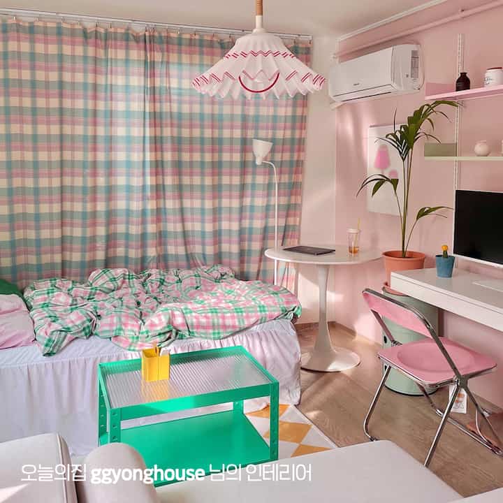 ピンクとミント色のワンルーム寝室、チェック柄の寝具とカーテンが配置された雰囲気のあるインテリア